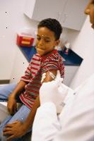 Φωτογραφία ενός νεαρού αγοριού ετοιμάζεται να πάρει έναν πυροβολισμό εμβολιασμού από τον γιατρό του