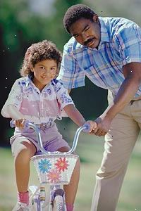 Εικόνα ενός πατέρα διδασκαλία κόρη του για να οδηγούν με ένα ποδήλατο