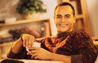 Εικόνα ενός νεαρού άνδρα χαμογελαστά, κρατώντας ένα φλιτζάνι καφέ