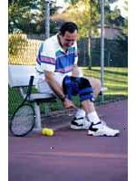 Εικόνα ενός άνδρα που φοράει ένα γόνατο-στήριγμα, παίζοντας τένις