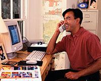 Εικόνα ενός άνδρα που εργάζεται στον υπολογιστή, να μιλά στο τηλέφωνο